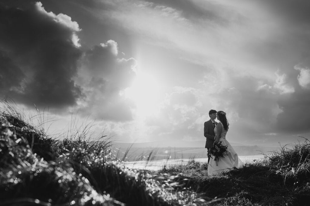 couple kiss with dramatic skies on beach in newport pembs