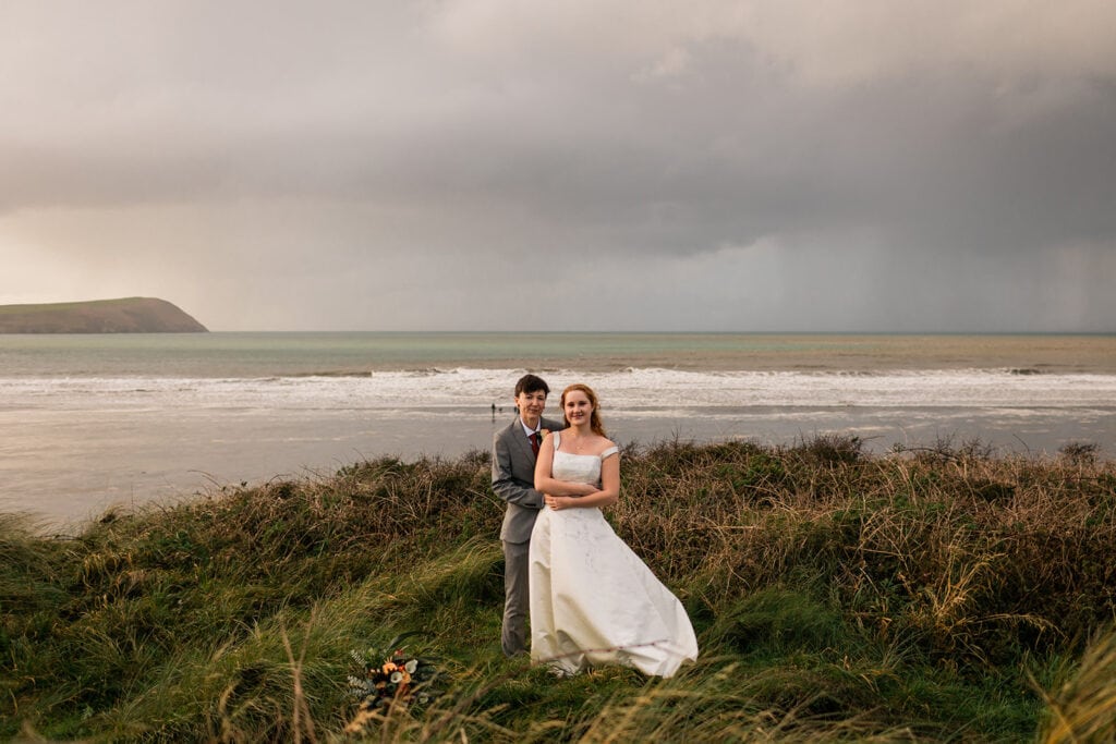 couple pose for wedding photo with stormy skies in background