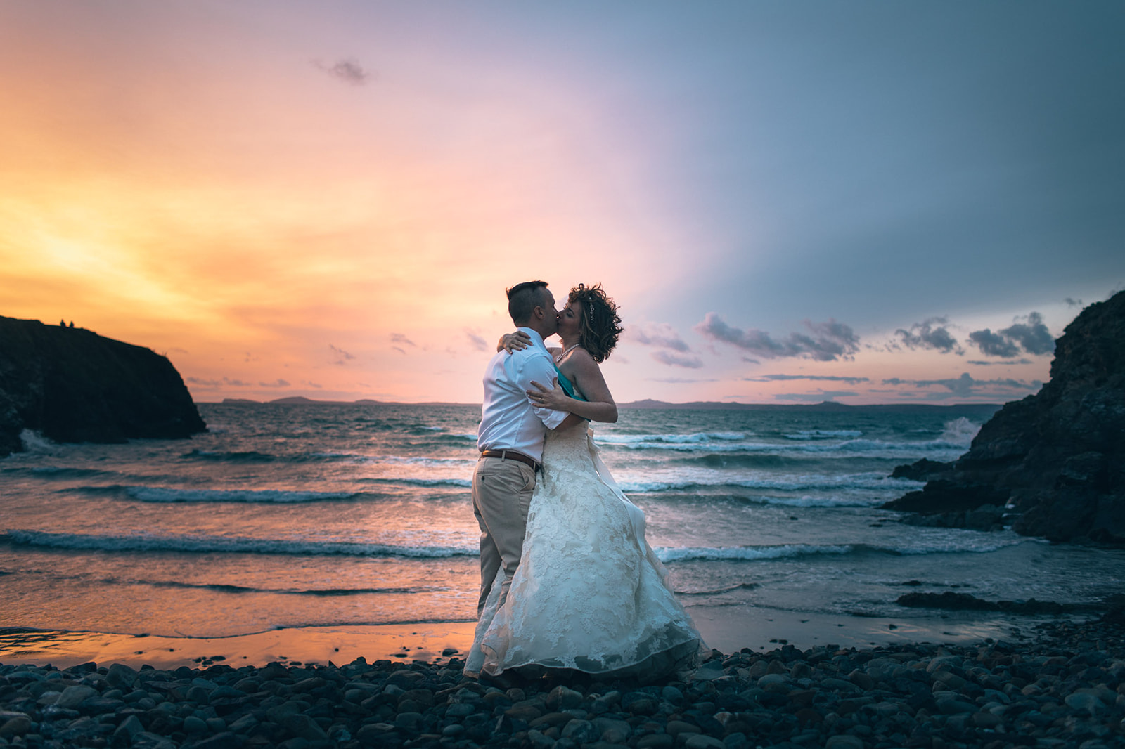 bride and groom kissing on beach at sunset