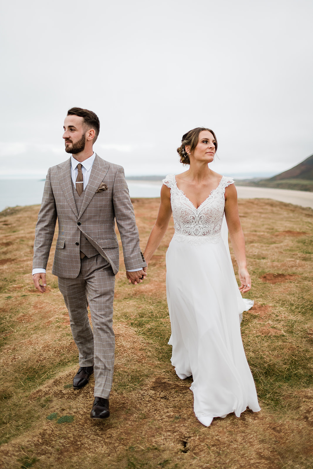 bride and groom walk along cliffs near beach