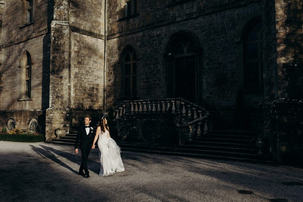 bride at groom walking in front of clearwell castle at a wedding